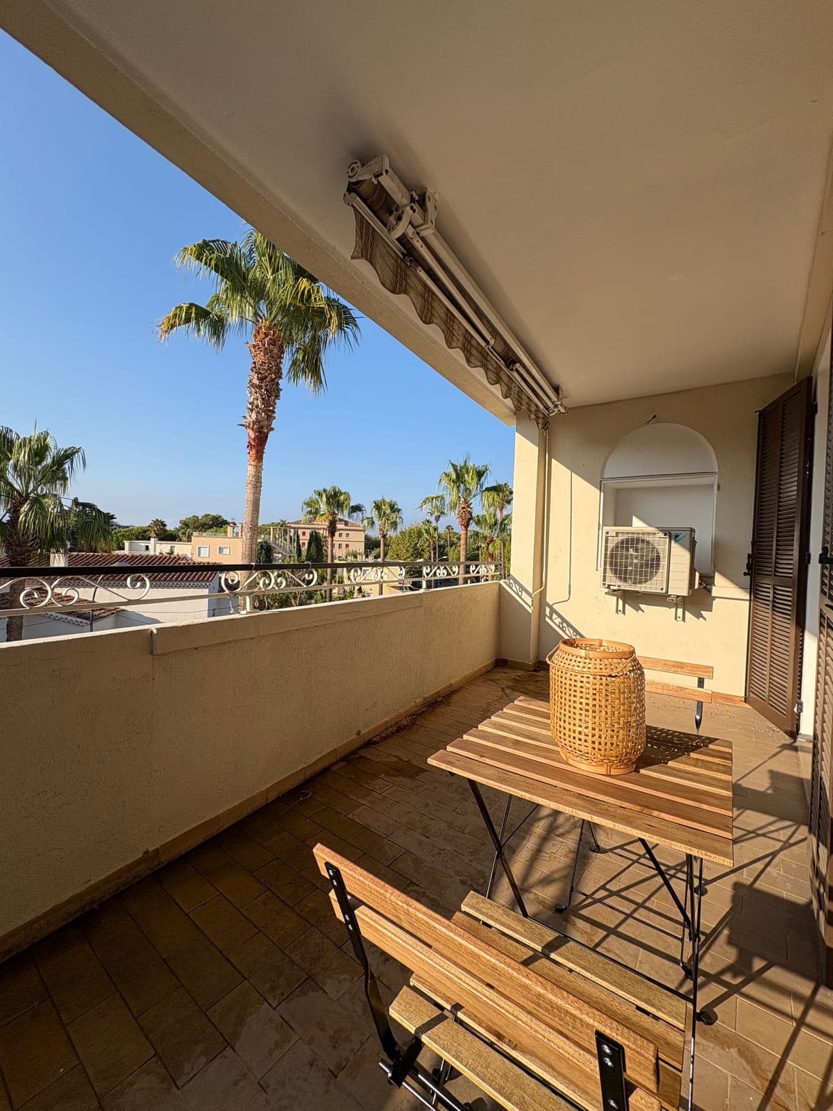 The balcony, set just above rooftops lined with palm trees — Sanary-sur-Mer — two apartment furnishing project